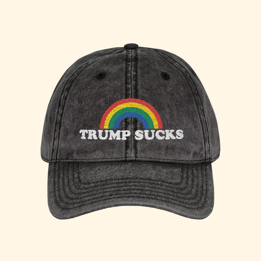 Black cap with rainbow and 'TRUMP SUCKS' text on a white background