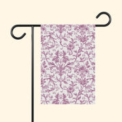 Decorative garden flag with pink floral pattern on a white background, attached to a black flagpole.
