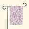 Decorative garden flag with pink floral pattern on a white background, attached to a black flagpole.