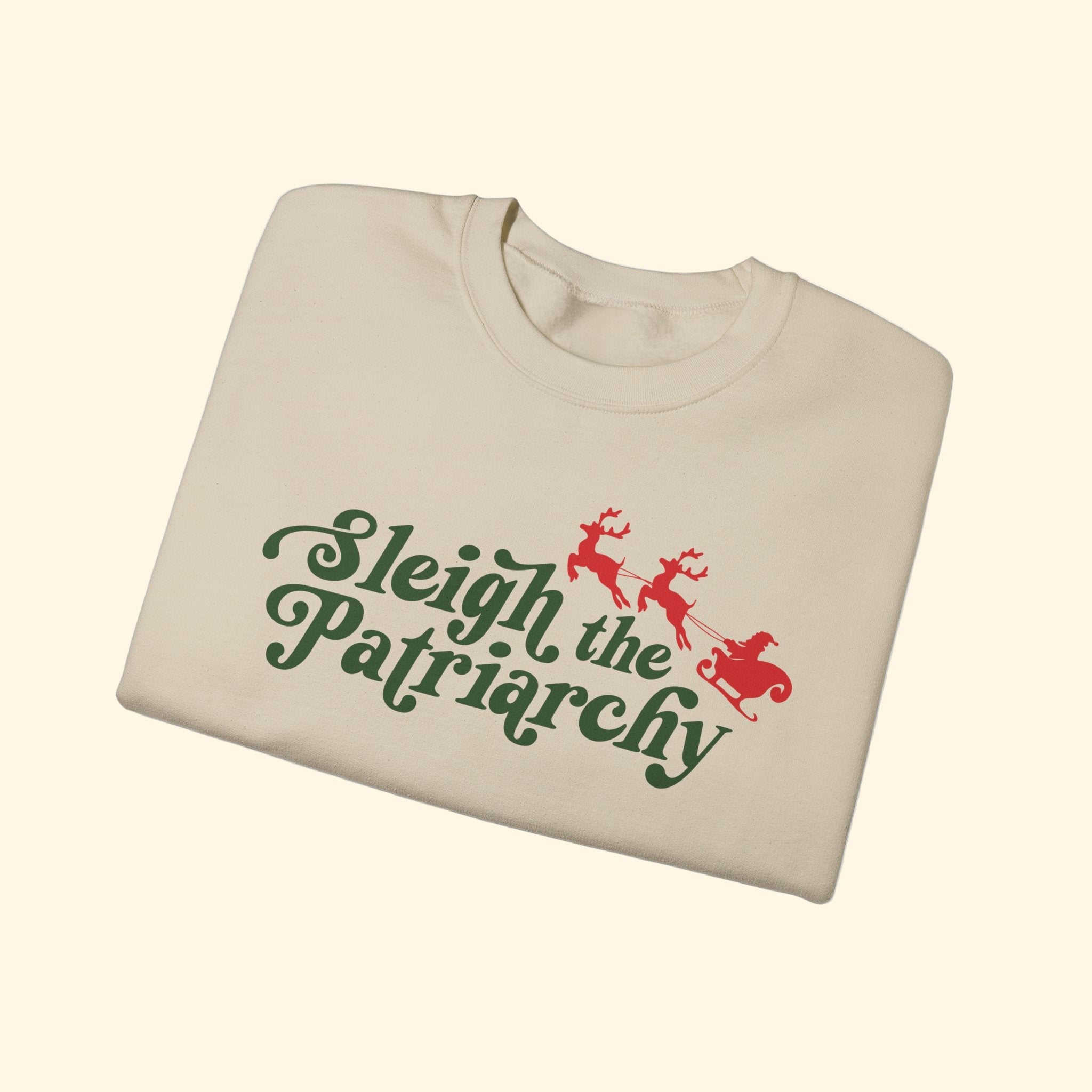 Beige sweatshirt with 'Sleigh the Patriarchy' text and reindeer graphic on a white background
