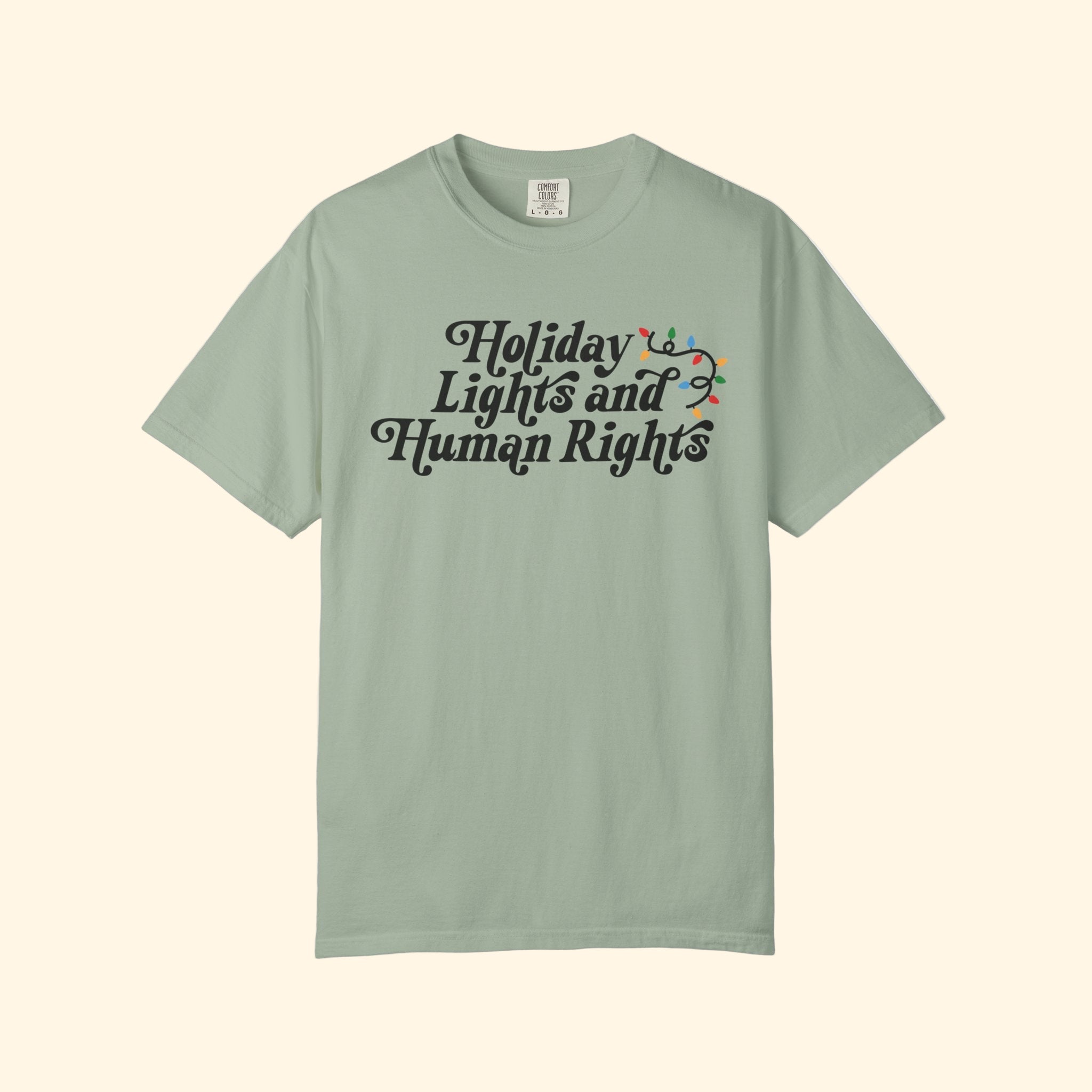 Green t-shirt with 'Holiday Lights and Human Rights' text on a white background