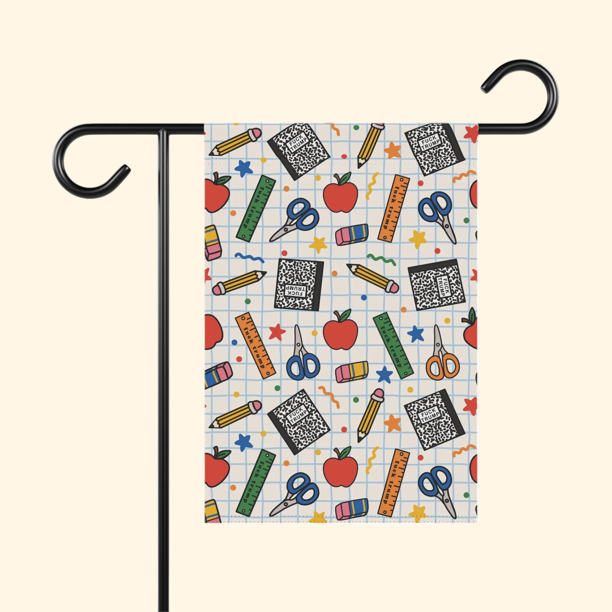 A garden flag with a colorful school supplies pattern, displayed on a black metal stand against a white background.