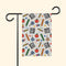 A garden flag with a colorful school supplies pattern, displayed on a black metal stand against a white background.