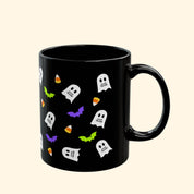 Black mug with Halloween-themed designs on a white background