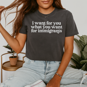 Person wearing a t-shirt with text, sitting indoors with plants in the background