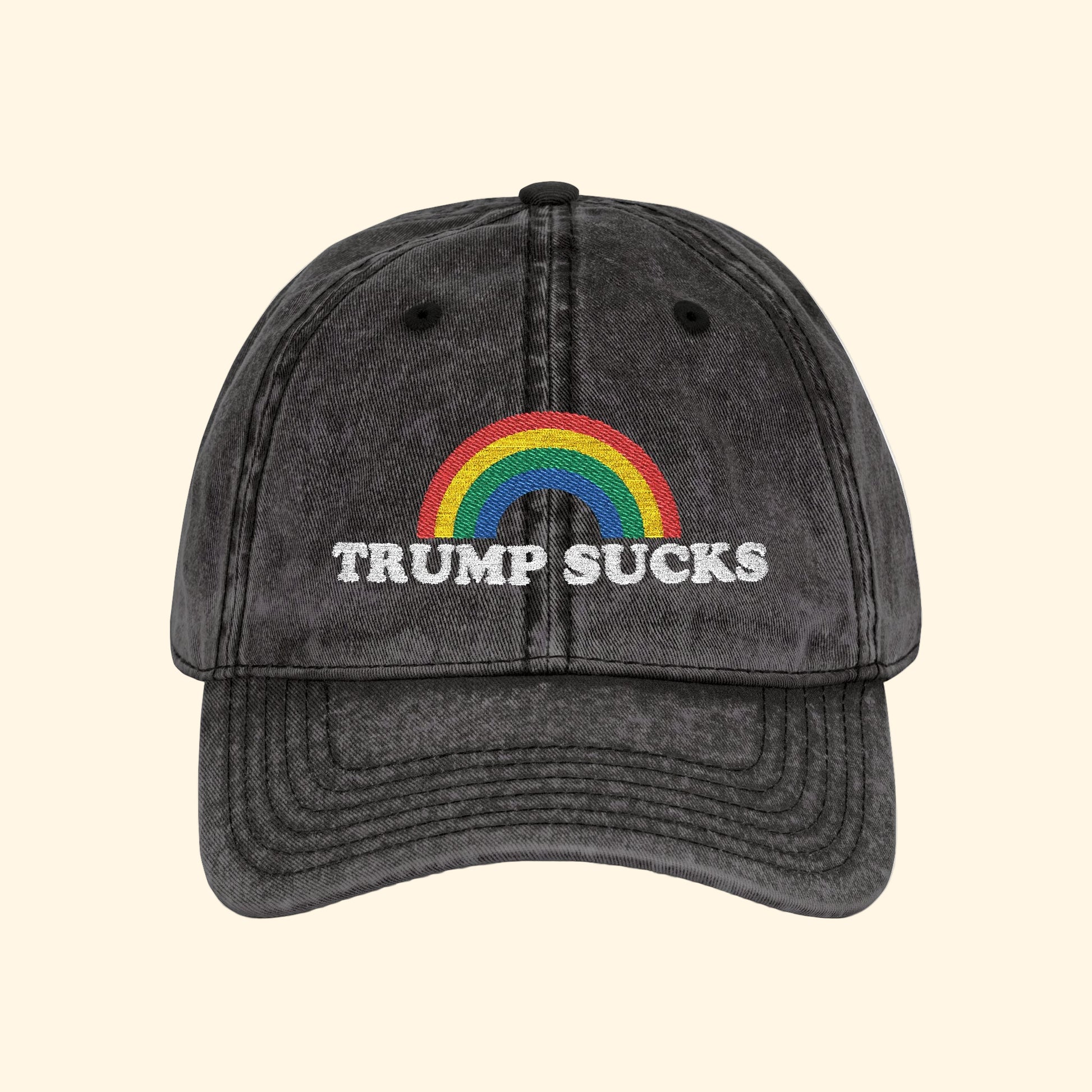 Black cap with rainbow and 'TRUMP SUCKS' text on a white background