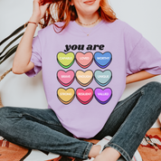 Person wearing a purple t-shirt with colorful heart-shaped affirmations.