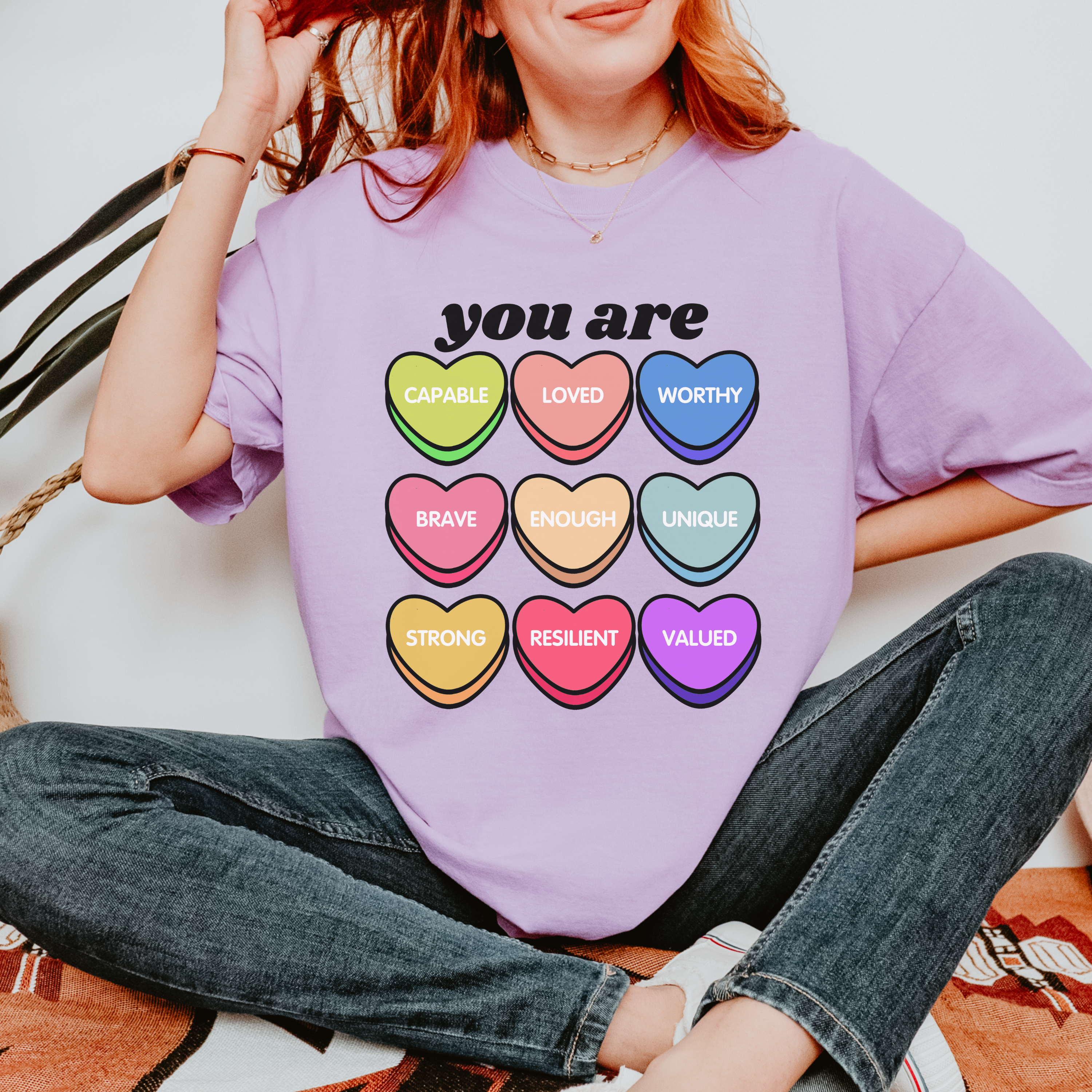 Person wearing a purple t-shirt with colorful heart-shaped affirmations.